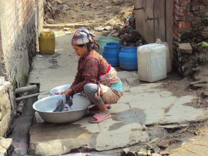 Mosó nő Khokanában. Nepálban a vízhez való hozzáférés is kihívást jelent. A hegyek eldugott falvaiban élő közösségeknek gyakran órákat kell utazniuk az ivóvízért, míg a nagyobb városok közelében a vízszennyezés a legnagyobb probléma. A Khokanától autóval 10 percre fekvő főváros, Katmandu napi 150 tonna szemetet termel, aminek majdnem fele végül a sokak vízellátását biztosító folyókban köt ki. Nem meglepő tehát, hogy a külföldi utazó számára ajánlatos elkerülni a csapvizet, és palackozottat használni akár öblögetéshez is.